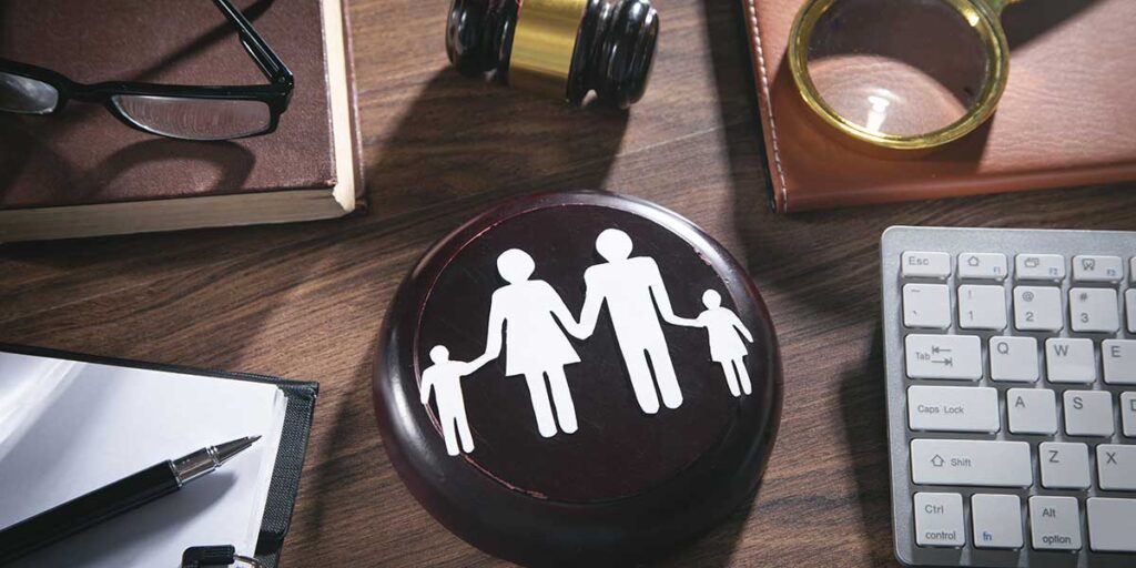 Legal documents, a keyboard, and a family cutout on a gavel rest on a desk for understanding family law pleadings.