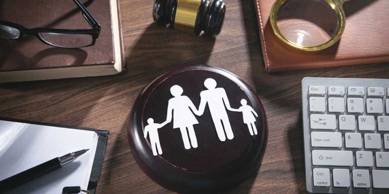 Legal documents, a keyboard, and a family cutout on a gavel rest on a desk for understanding family law pleadings.