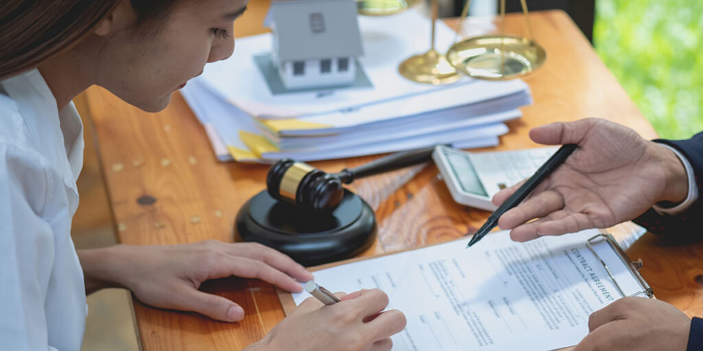 A woman reviewing legal contract documents with an attorney to handle ancillary probate proceedings for an out-of-state property.